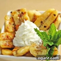 Bowl of Caribbean bananas caramelized in butter, brown sugar, rum, and lime, topped with whipped cream and garnished with fresh mint.