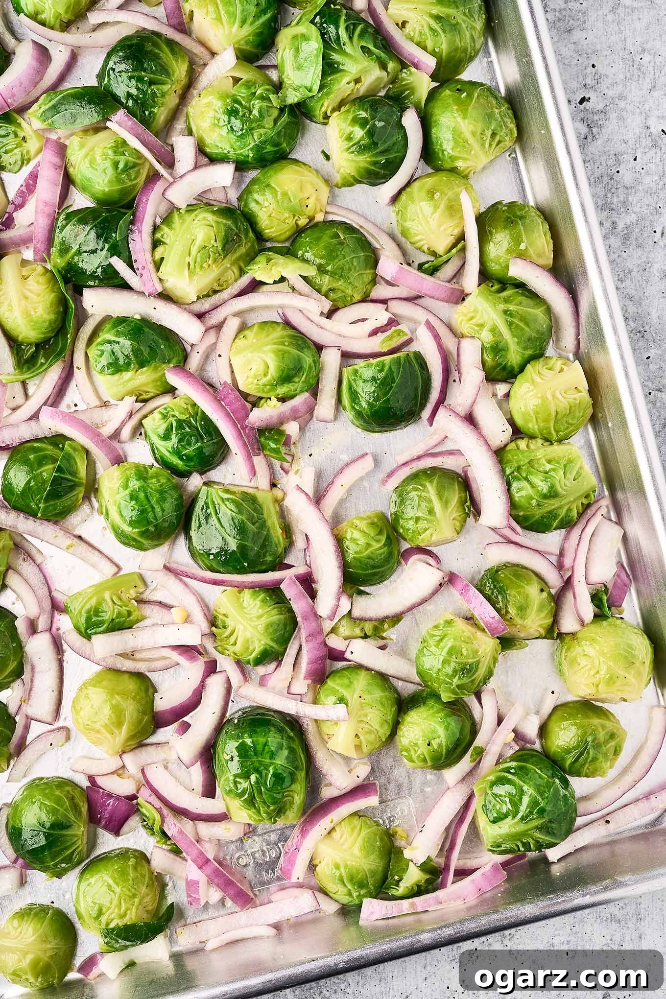 Bold Blue Brussels Sprouts 4 Blanched Brussels sprouts, cut in half and spread on a baking sheet with slices of red onion, ready to be roasted.