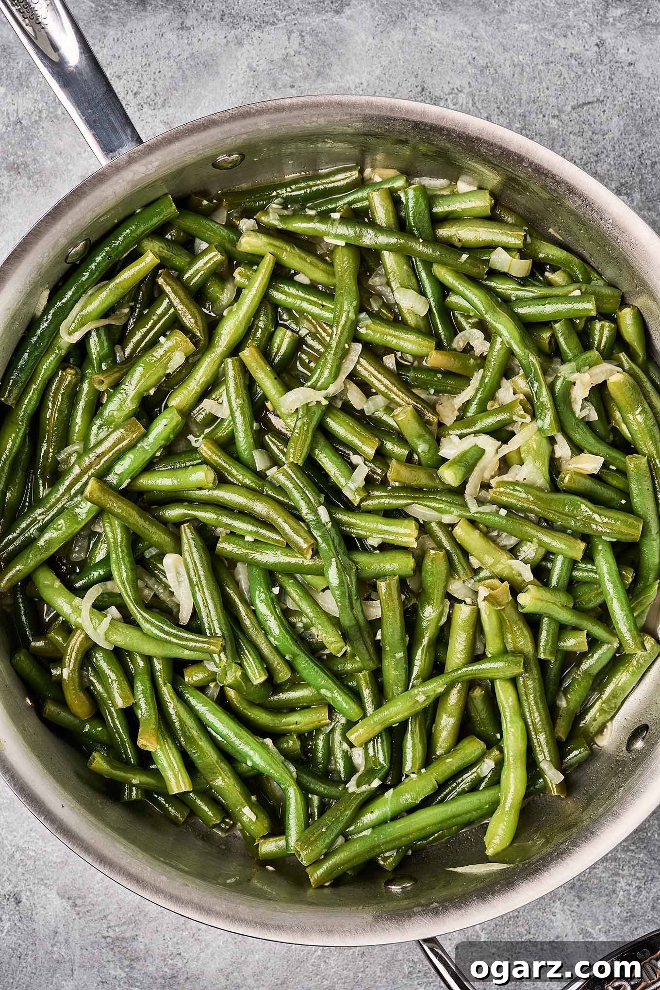 Golden Crumb Green Bean and Mushroom Medley 5 Fresh green beans simmering in broth with sautéed onions and garlic in a skillet, capturing the initial cooking stage for green beans and mushrooms with crumb topping.