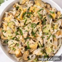Serving bowl filled with snail (scungilli) salad with celery, onion, parsley, and crushed red pepper.