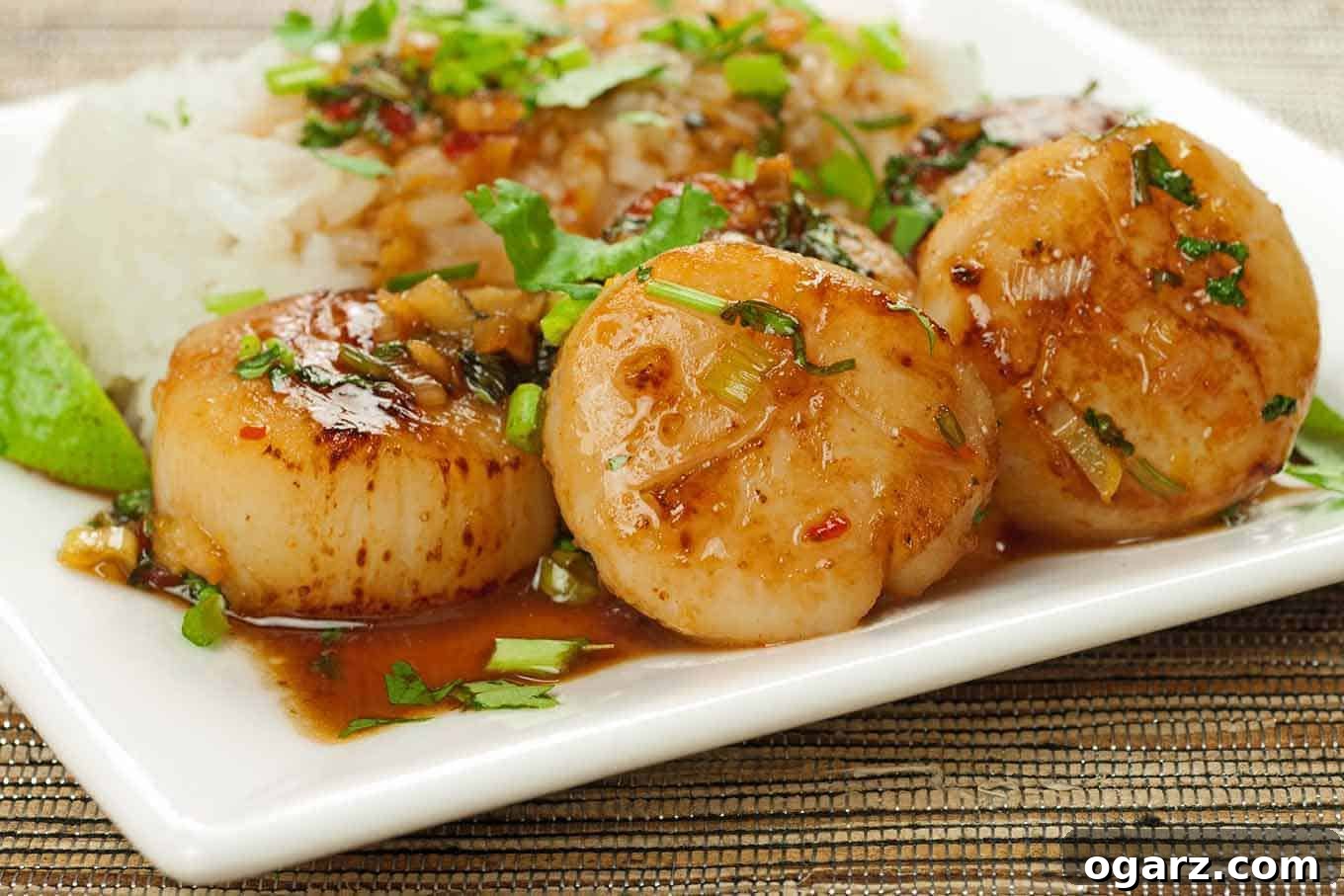 Exquisite Thai Sweet Chili and Orange Scallops, perfectly seared and glazed, served with steamed rice and fresh herbs.