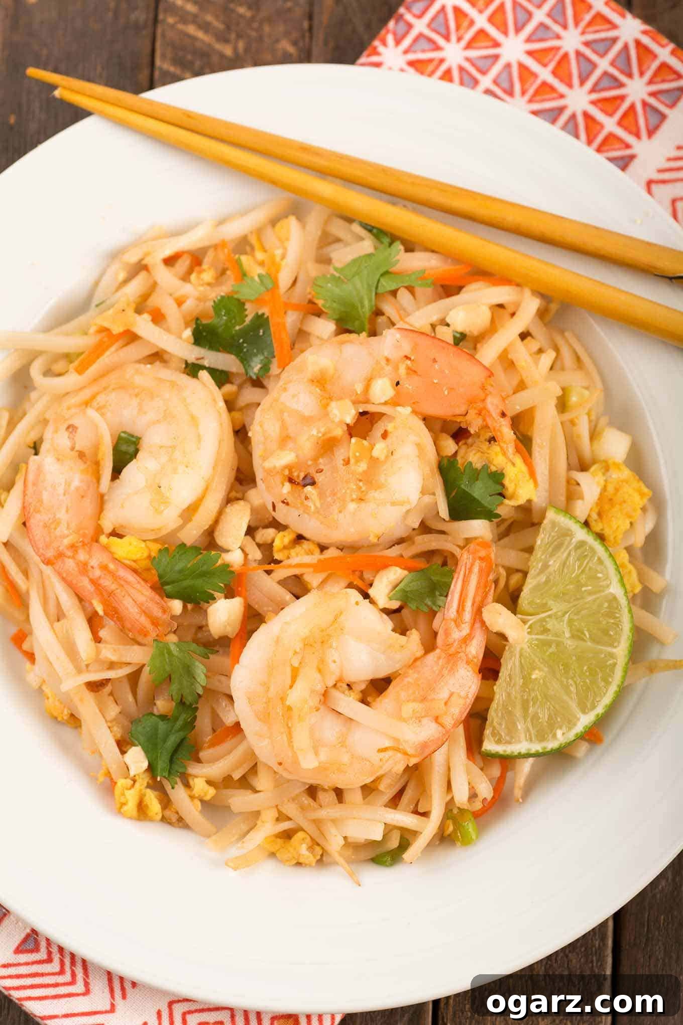 Classic Shrimp Pad Thai Delight 4 A beautifully plated single serving of shrimp Pad Thai on a pristine white plate, accompanied by a fresh lime wedge and a pair of chopsticks, ready to be enjoyed.