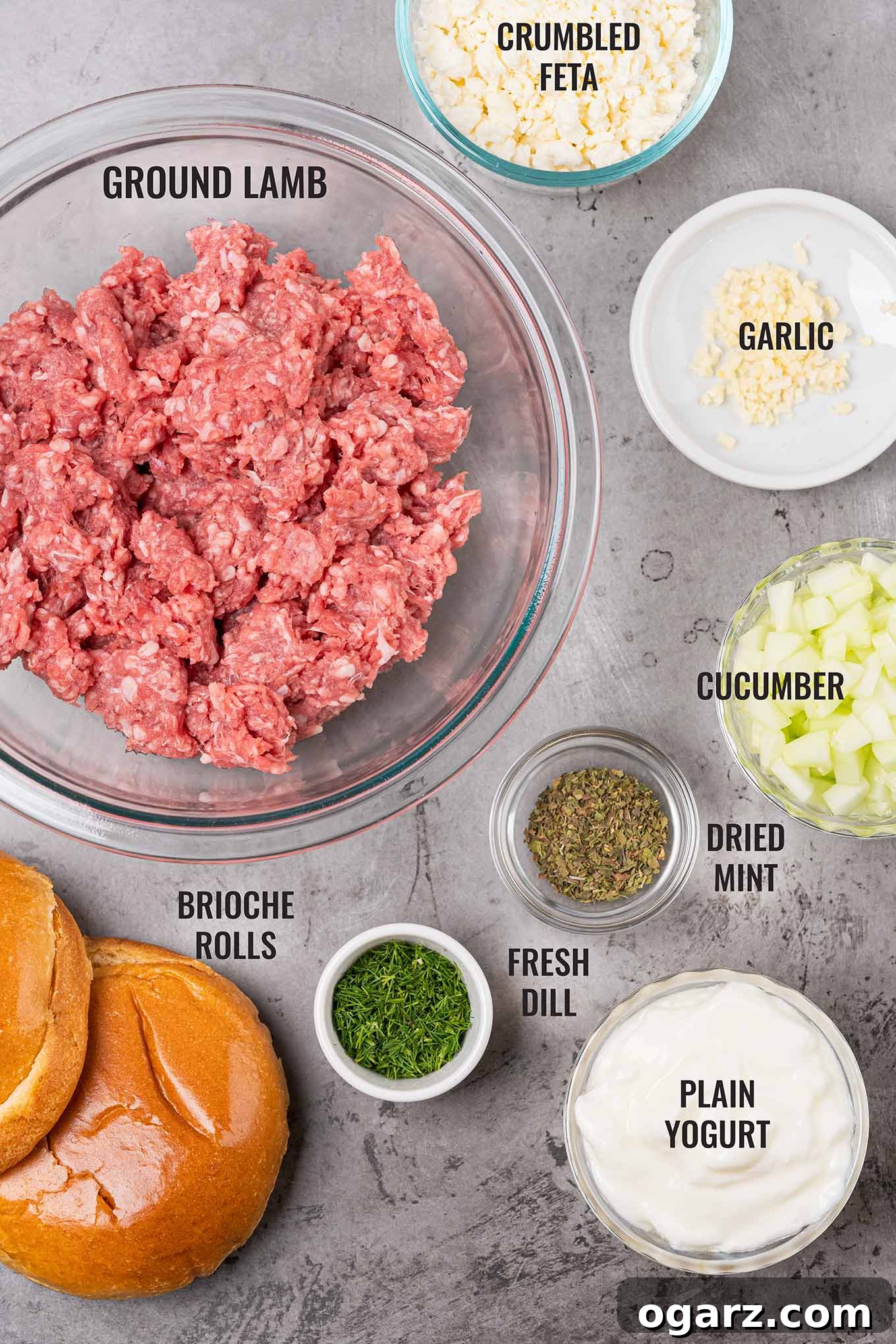 Grecian Lamb & Herb Burgers 3 A labeled, overhead view of all the grilled lamb burger and tzatziki sauce ingredients including ground lamb, brioche rolls, dried mint, cucumber, yogurt, and more.