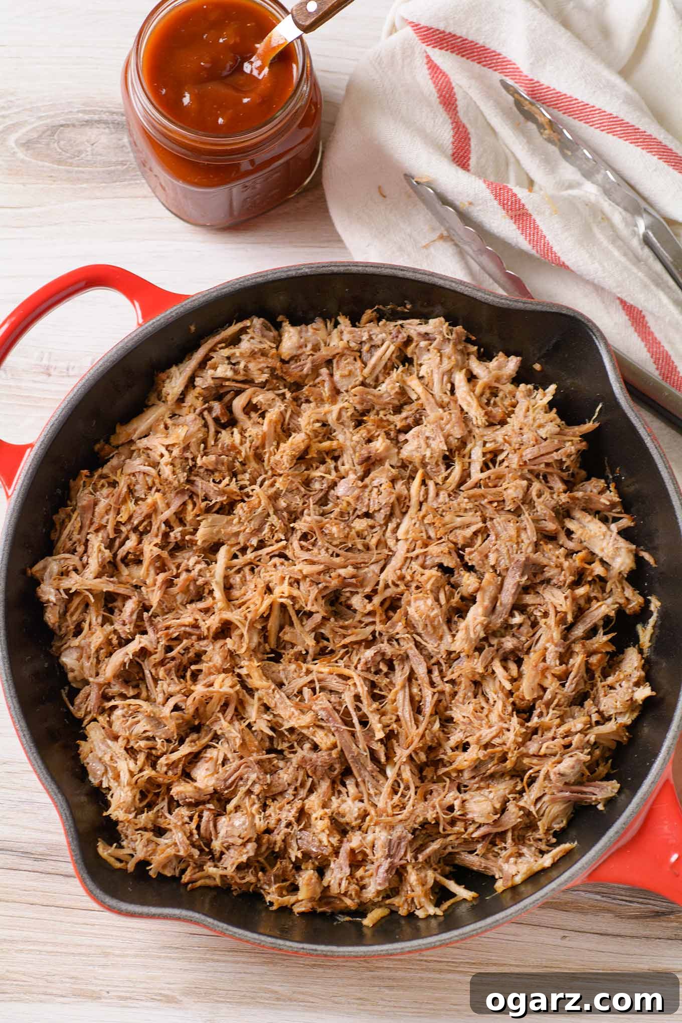 Perfectly Tender Oven-Roasted Pulled Pork 4 An overhead view of pulled pork in a cast iron pan, showing the texture before any sauce is added.