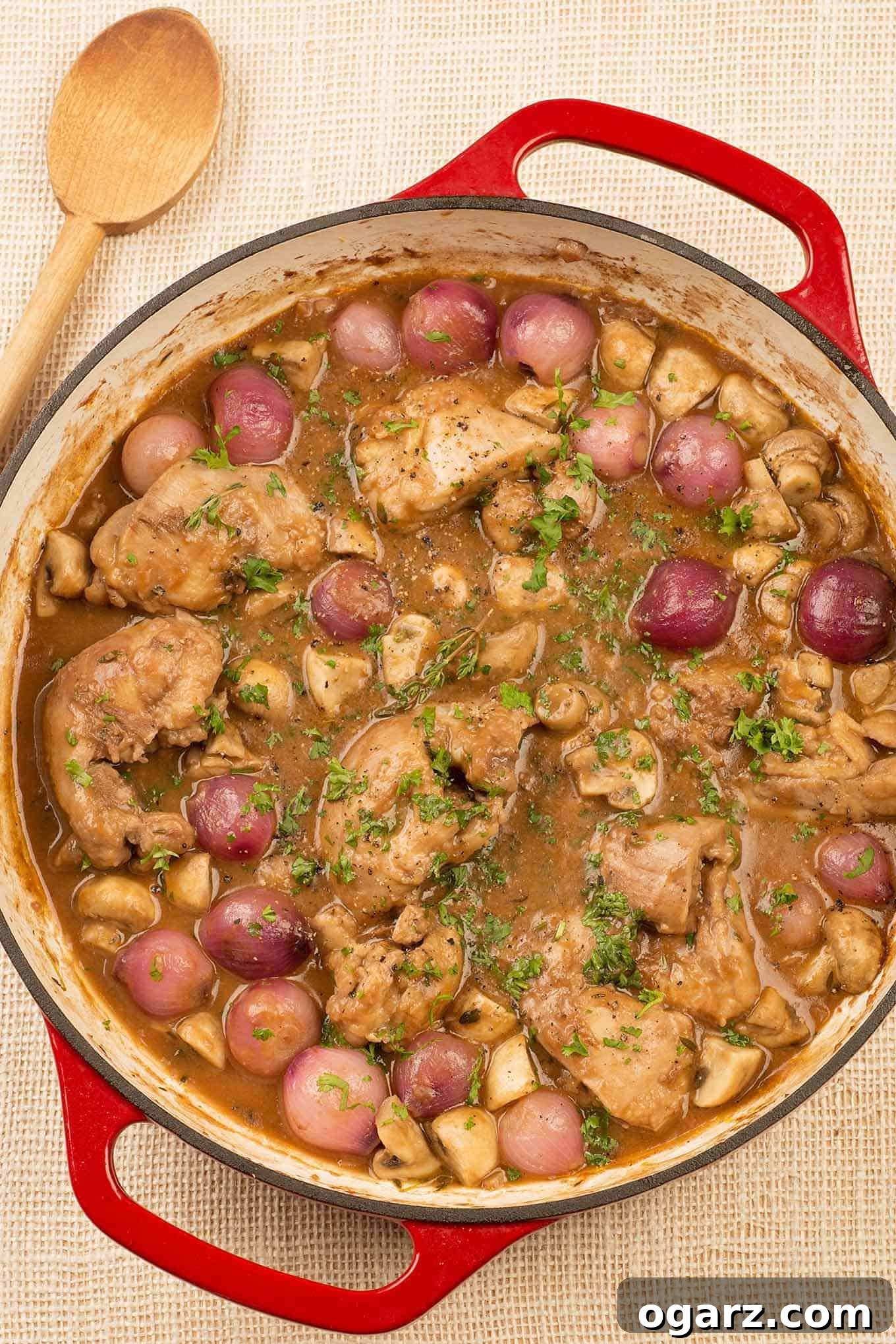 Slow-Braised Red Wine Chicken Thighs 2 A cast iron pan filled with boneless chicken thighs braised in red wine with bacon, thyme, mushrooms, and pearl onions.