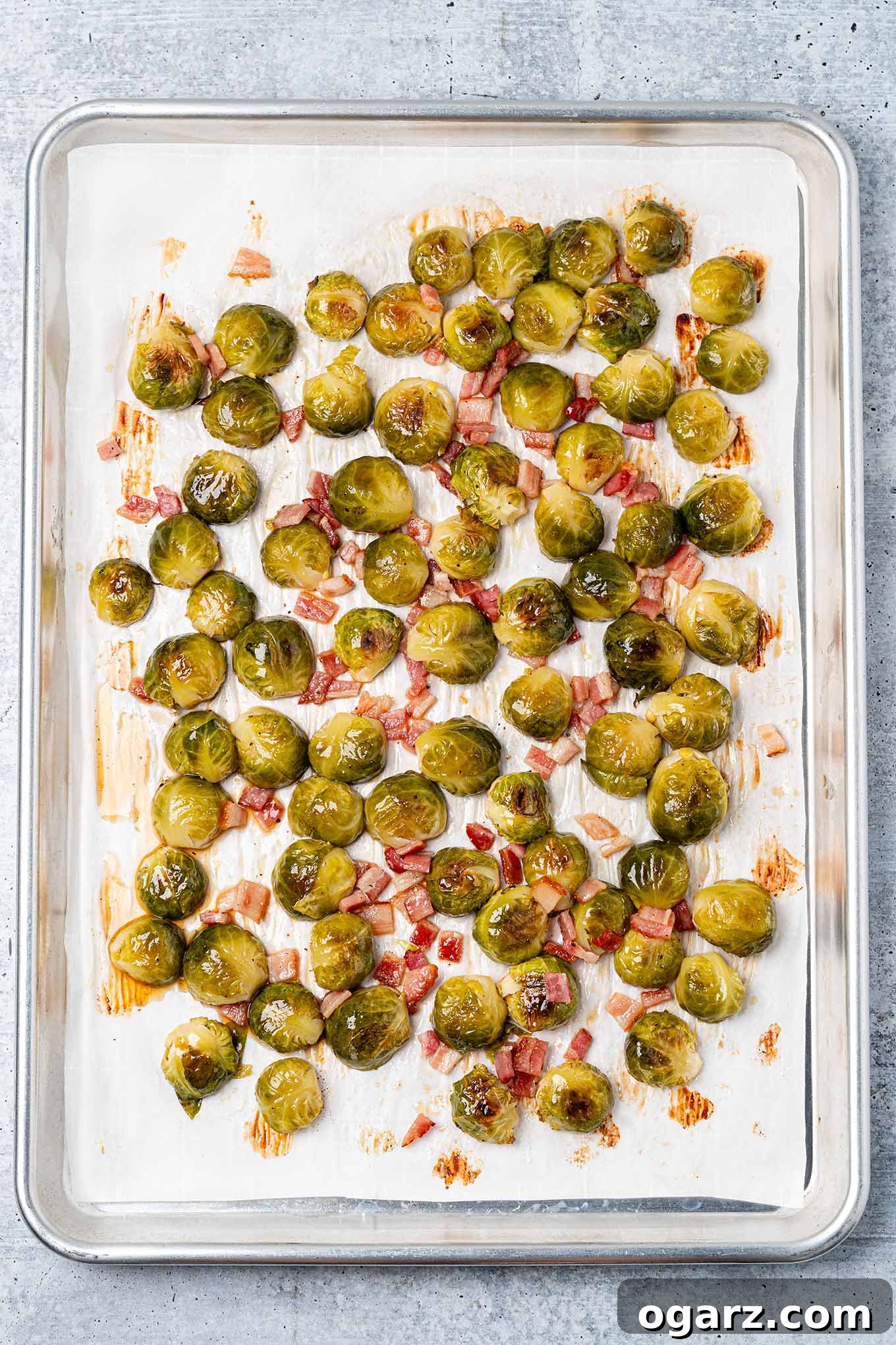 Caramelized Maple Brussels with Crispy Bacon 4 Maple glazed Brussels sprouts and bacon on a baking sheet ready to be turned and finish roasting.