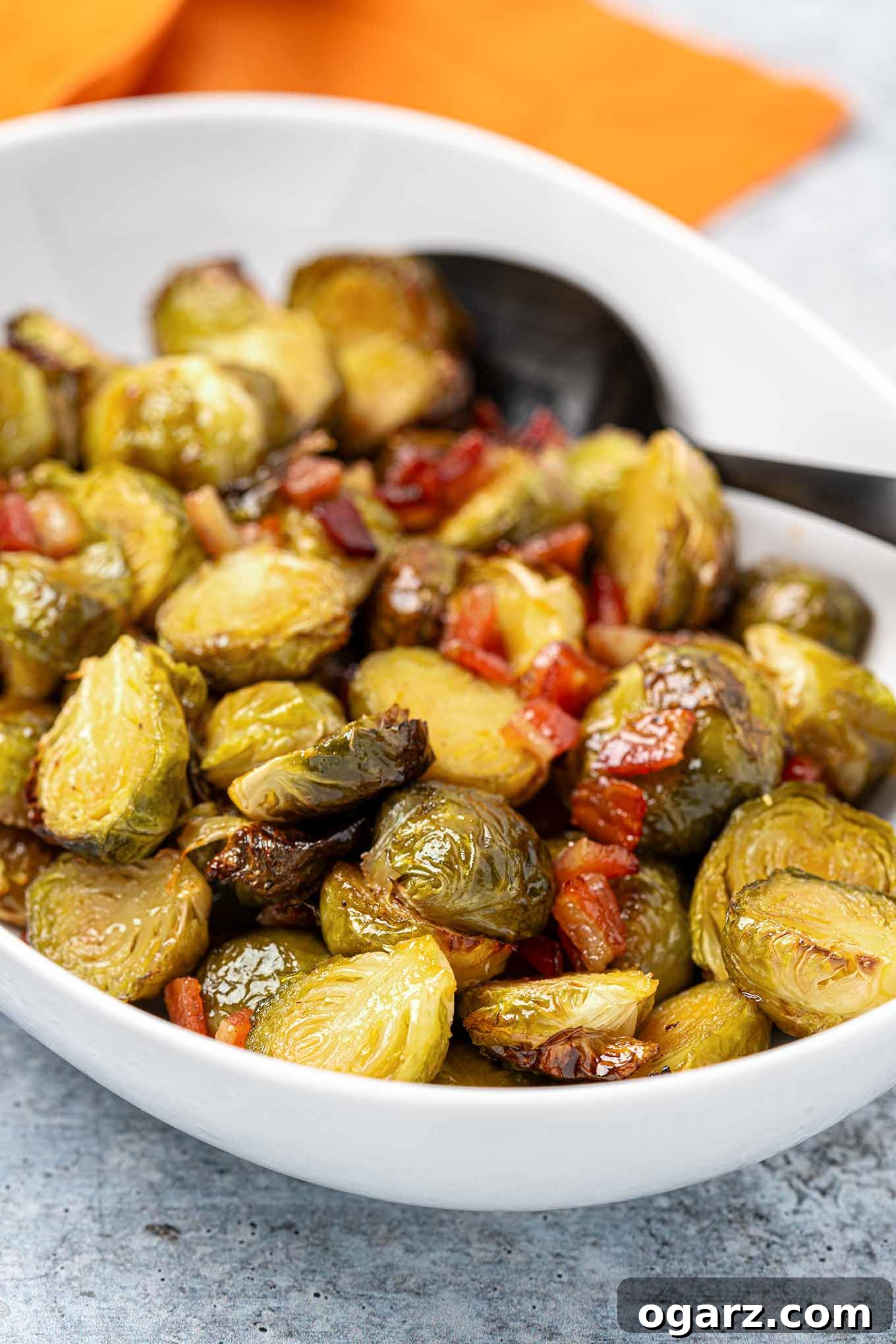 Caramelized Maple Brussels with Crispy Bacon 6 Roasted maple glazed Brussels sprouts with bits of bacon in a white serving bowl.