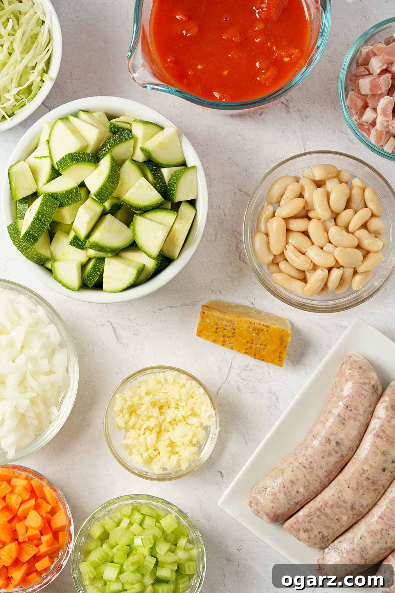 Savory Sausage Minestrone Bowl 3 An overhead view of the ingredients for minestrone soup; Italian sausage, zucchini, cannellini beans, pancetta, carrots, celery, onion, and more.