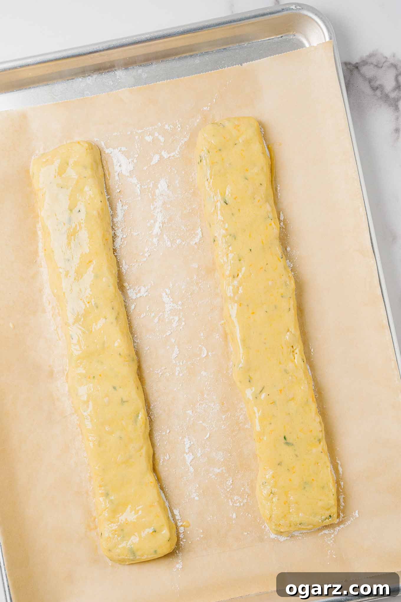 Golden Buttery Orange Biscotti 4 Logs of orange biscotti dough on a parchment-lined baking sheet ready for the first baking in the oven.