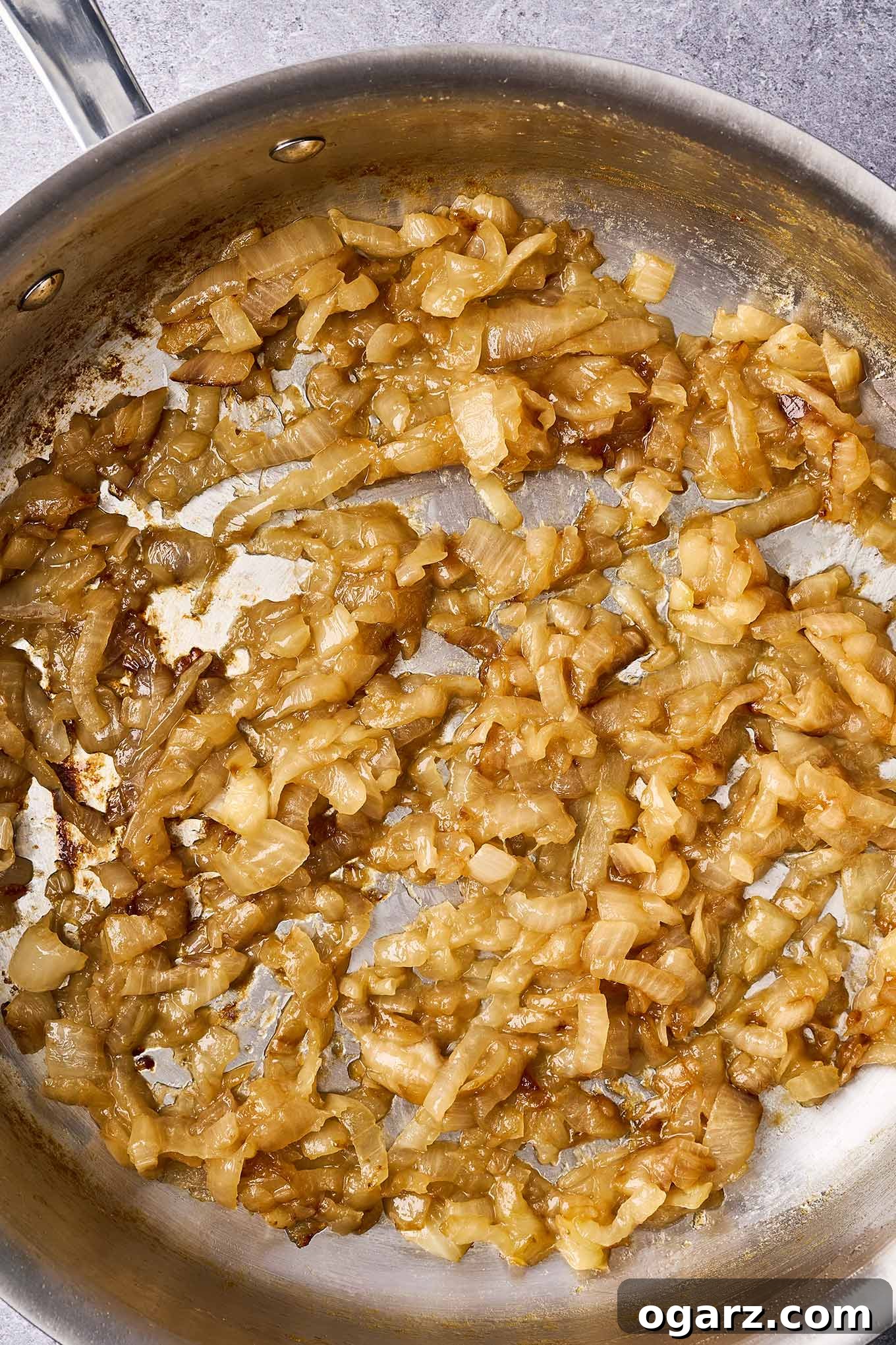 Mastering Caramelized Onions From Pan to Perfection 2 A stainless steel skillet brimming with perfectly caramelized onions, showcasing their rich, golden-brown hue and jam-like texture. A culinary staple for enhancing a myriad of dishes.
