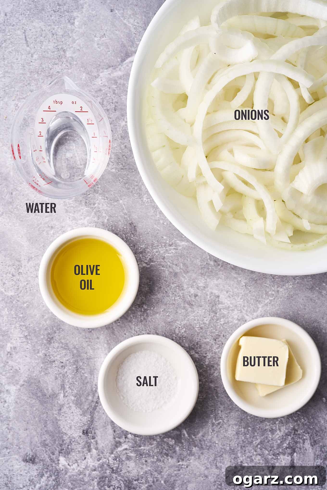 Mastering Caramelized Onions From Pan to Perfection 3 A neatly arranged overhead photo displaying the essential ingredients for making caramelized onions: precisely sliced yellow onions, high-quality olive oil, a stick of butter, a sprinkle of salt, and a small container of water for deglazing.