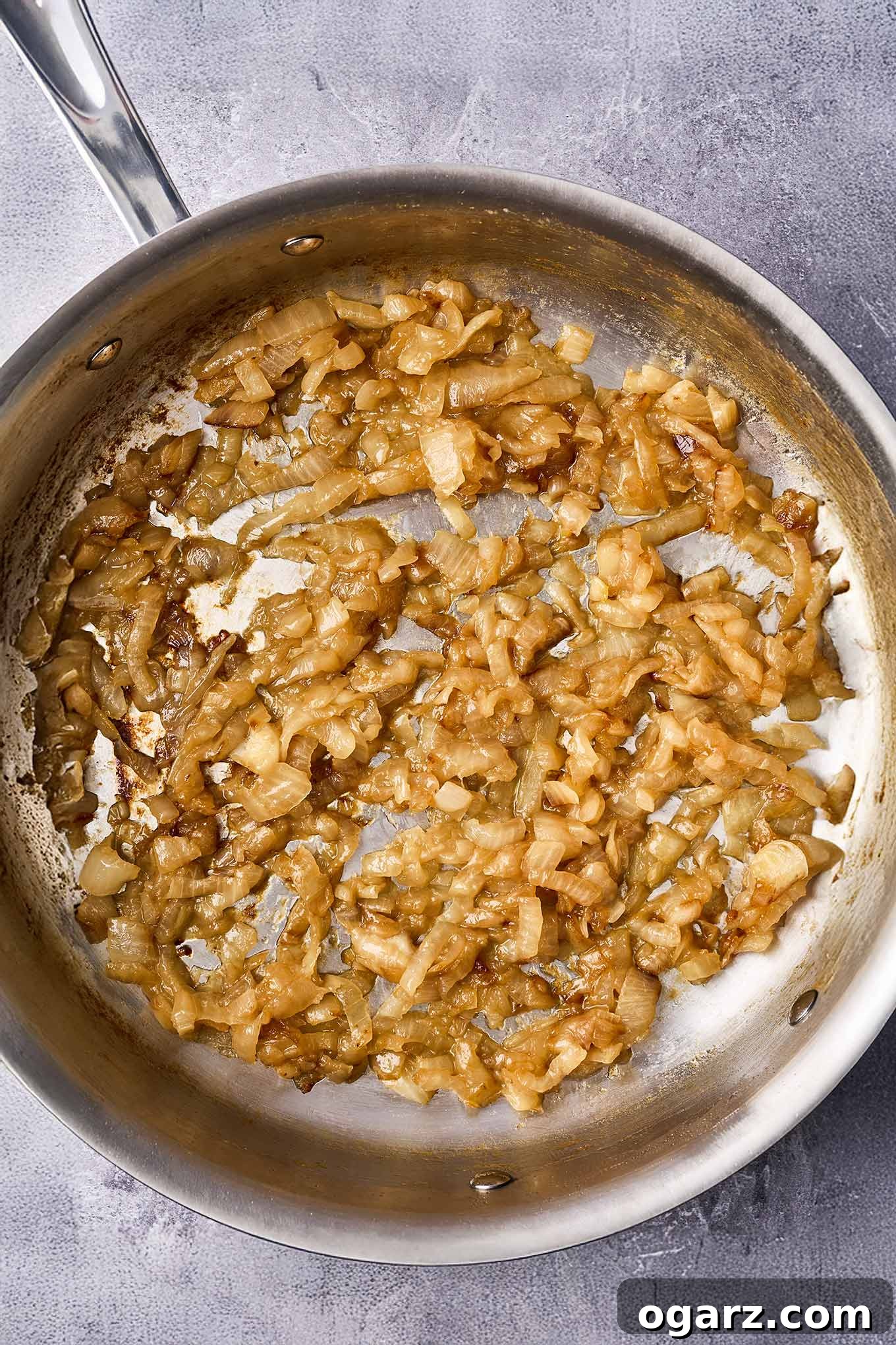 Mastering Caramelized Onions From Pan to Perfection 4 Caramelized onions in a stainless skillet, cooked down to a partially spreadable consistency, retaining some texture for about 35 to 40 minutes of cooking.