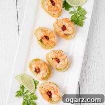 A serving platter filled with shrimp and avocado crostini and garnished with cilantro and lime.