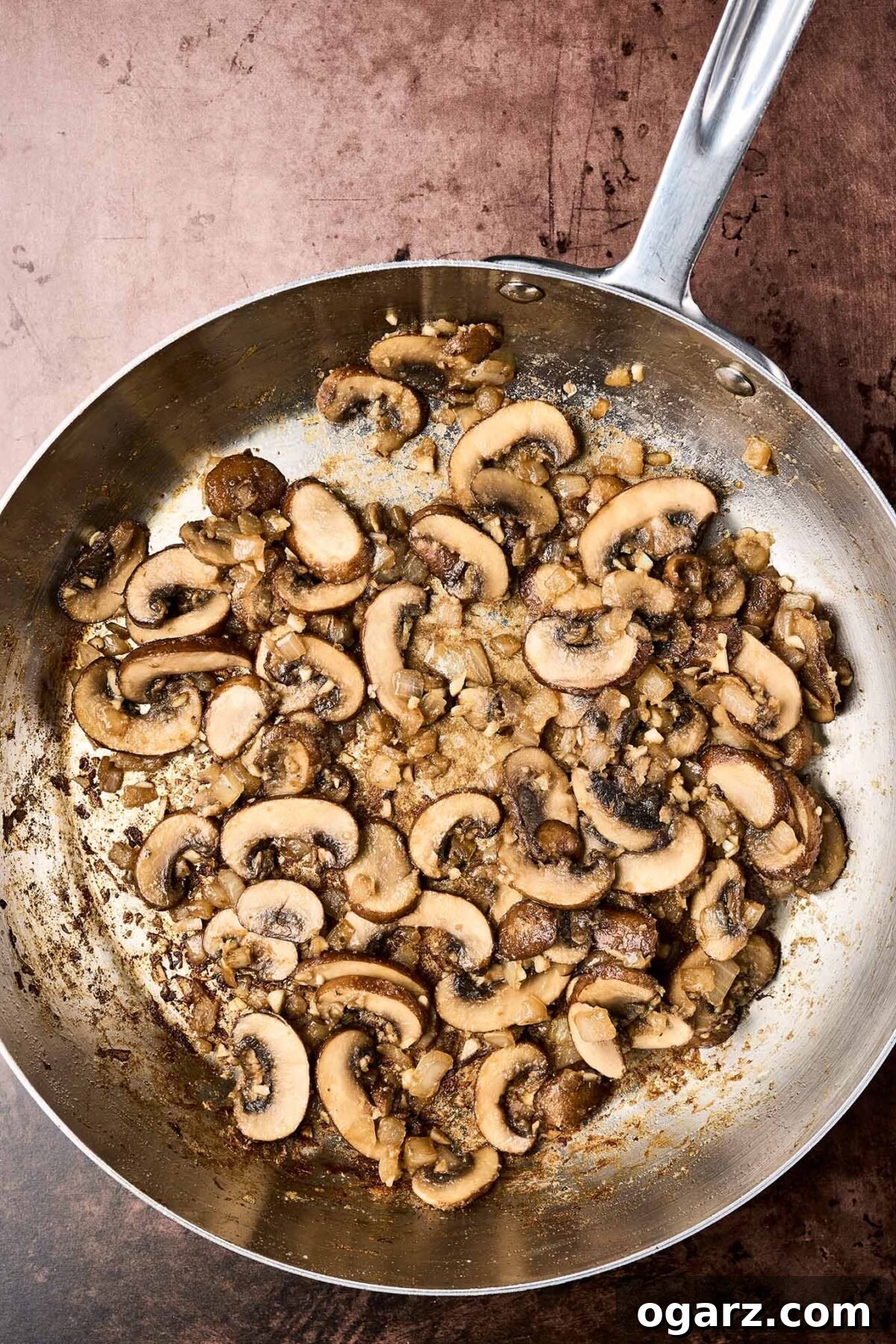 Savory Marsala Chicken and Tomato Pasta 4 A frying pan showing beautifully browned mushrooms with garlic and onions, ready for the addition of Marsala wine to make a sauce.