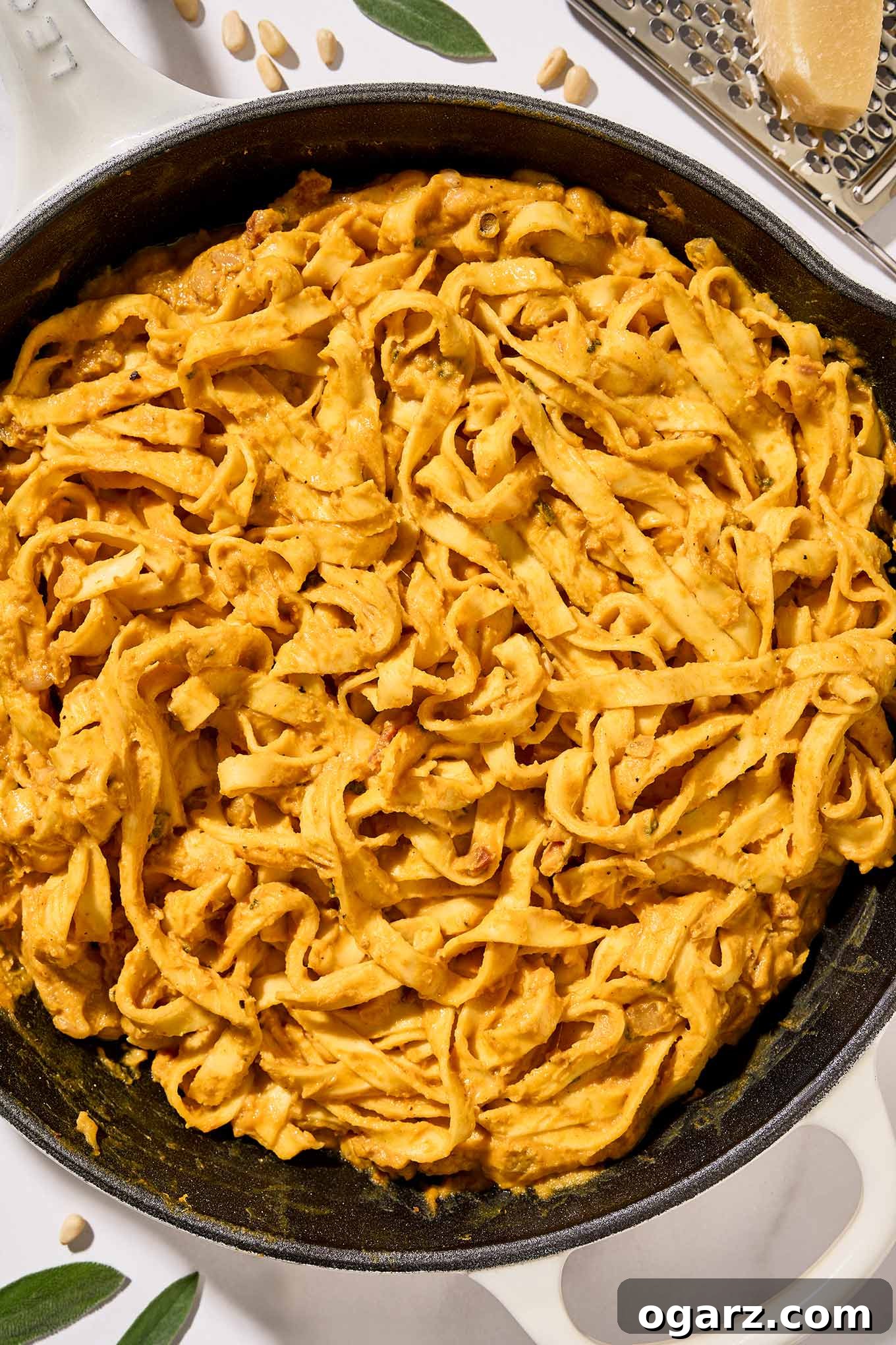 The last step for preparing creamy pumpkin pasta, fettuccine combined with pumpkin puree, pancetta, pine nuts, sage, and half and half.