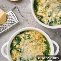 Spinach Pasta Stracciatella Soup 7 Bowls of stracciatella soup with spinach, ditalini, and grated Parmigiano-Reggiano, shown with bread and a cheese grater.