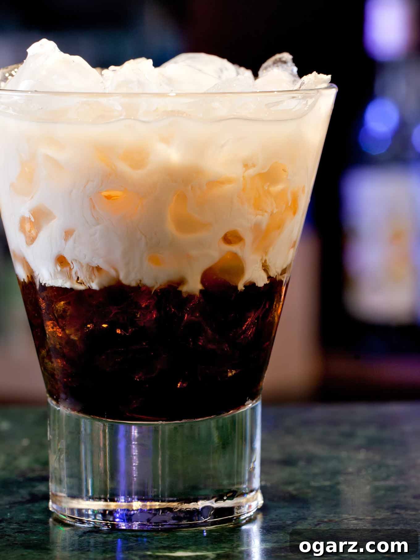 White Russian cocktail served over ice in a short glass, with layers of cream and coffee liqueur swirling together.