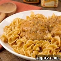 Creamy chicken paprikash featuring tender chicken thighs in a smooth, paprika-infused sauce, nestled on a bed of egg noodles.