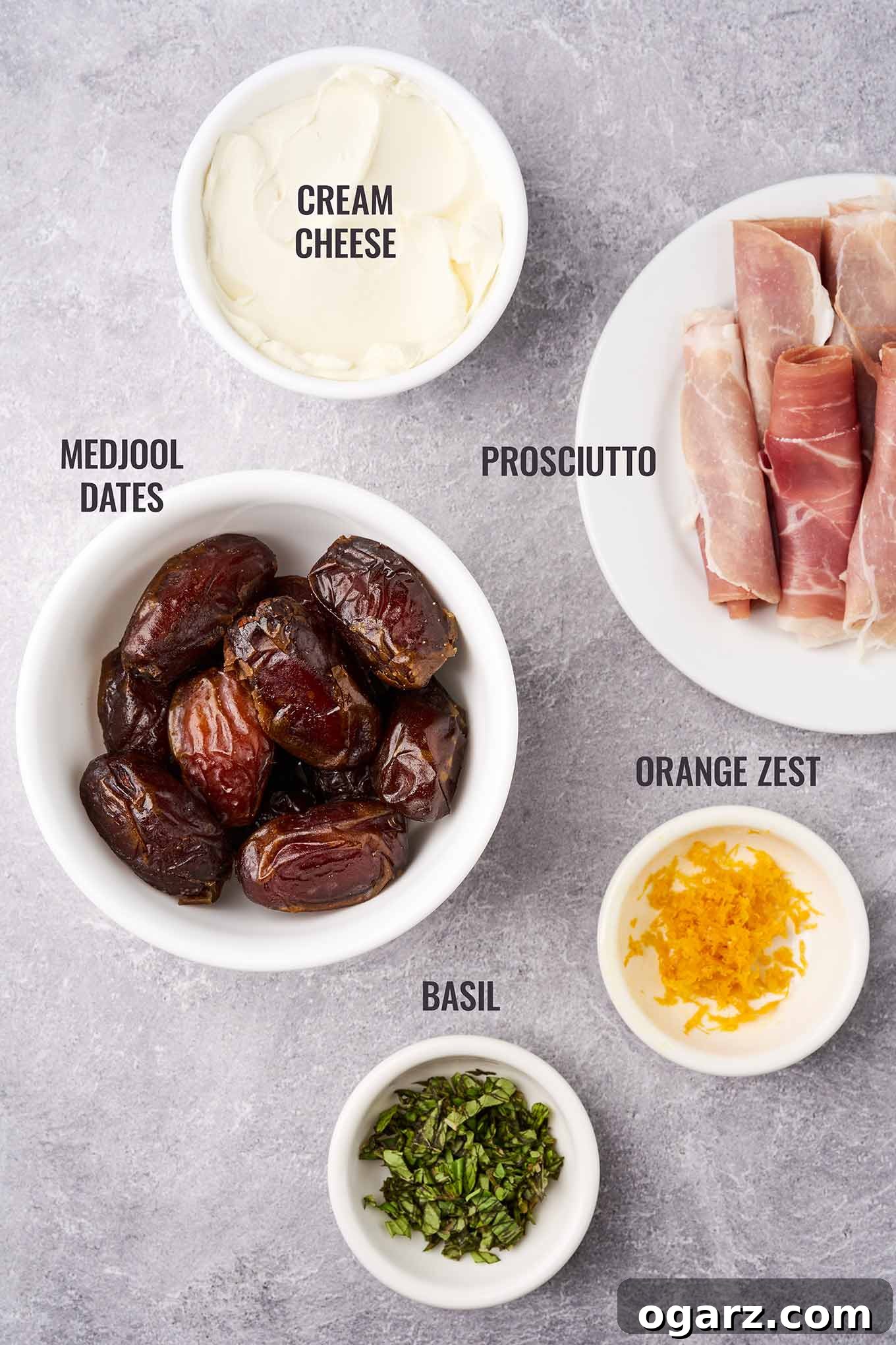 A labeled, overhead view of the ingredients needed for stuffed dates including Medjool dates, prosciutto, cream cheese, fresh basil, and orange zest.