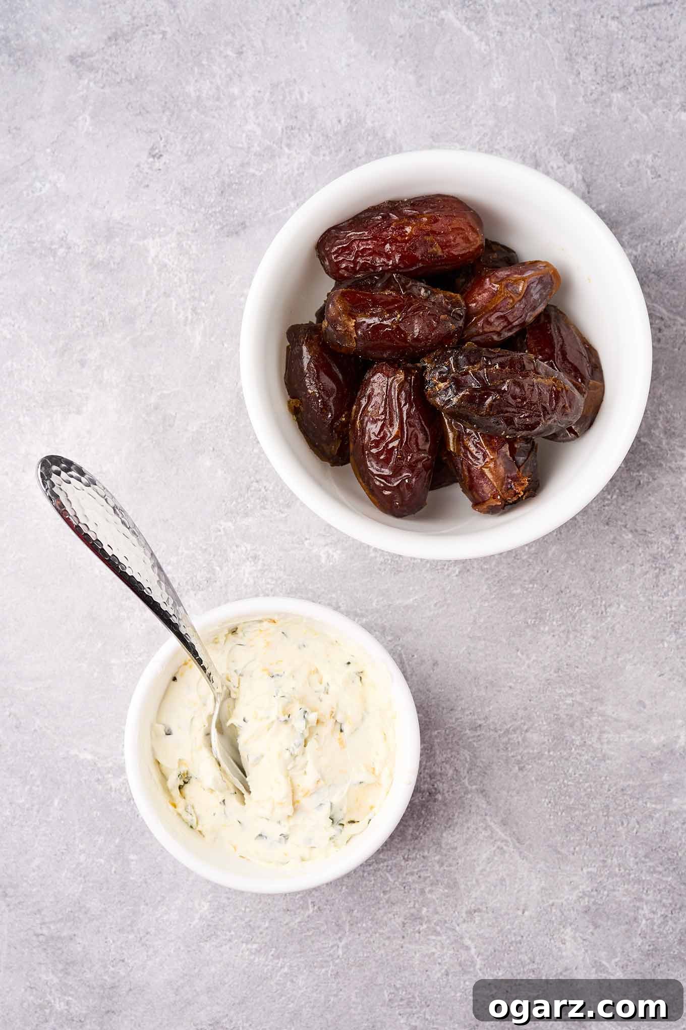 A bowl of Medjool dates next to a bowl of cream cheese, basil, and orange zest filling, ready to make stuffed dates.