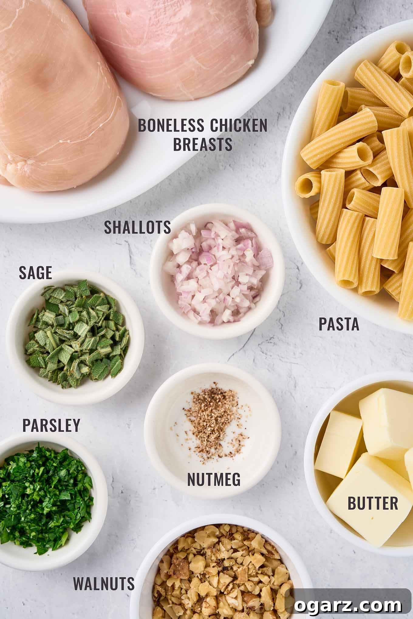 Nutty Brown Butter Chicken Pasta 3 A labeled, overhead view of the ingredients for brown butter pasta with chicken; boneless chicken breasts, rigatoni, shallots, sage, parsley, nutmeg, butter, and walnuts laid out beautifully.