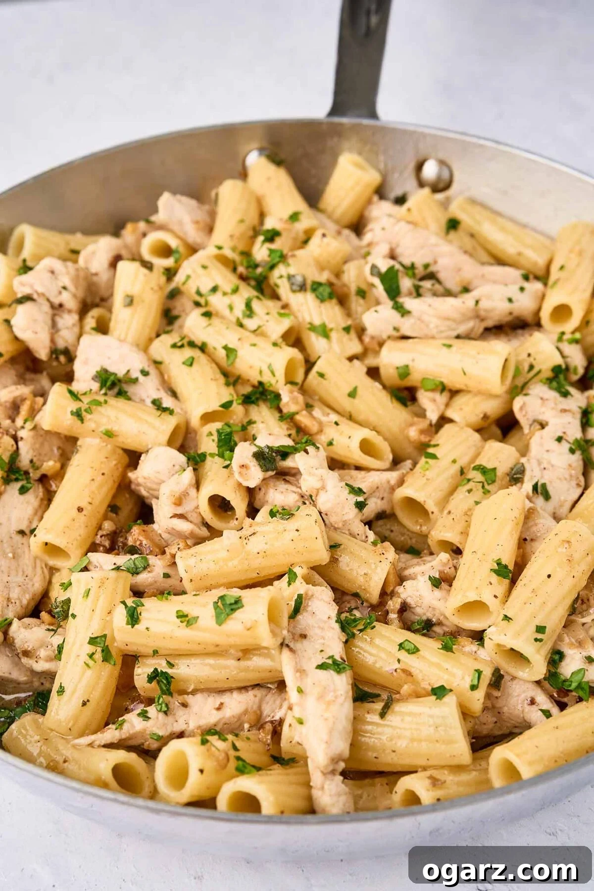 Nutty Brown Butter Chicken Pasta 8 The final step for preparing brown butter chicken pasta - combining the cooked pasta, brown butter, shallots, walnuts, and herbs, and sautéed chicken, then dusting it with nutmeg for a warm, aromatic finish.