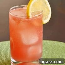 Chilled Watermelon-Limoncello Collins cocktail with ice, garnished with a lemon slice on the rim of the glass.