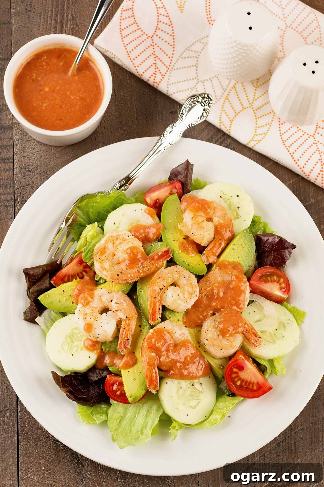 Zesty Shrimp Cocktail Salad 2 Vibrant shrimp cocktail salad with mixed greens, creamy avocado, crisp cucumber, ripe tomatoes, and succulent shrimp drizzled with tangy cocktail sauce dressing.