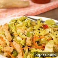 Zesty Pork and Napa Slaw 4 A spicy salad of napa cabbage, shredded carrots, red bell pepper, and scallions topped with stir-fried pork, a bottle of sriracha and knob of ginger on a towel in the background.