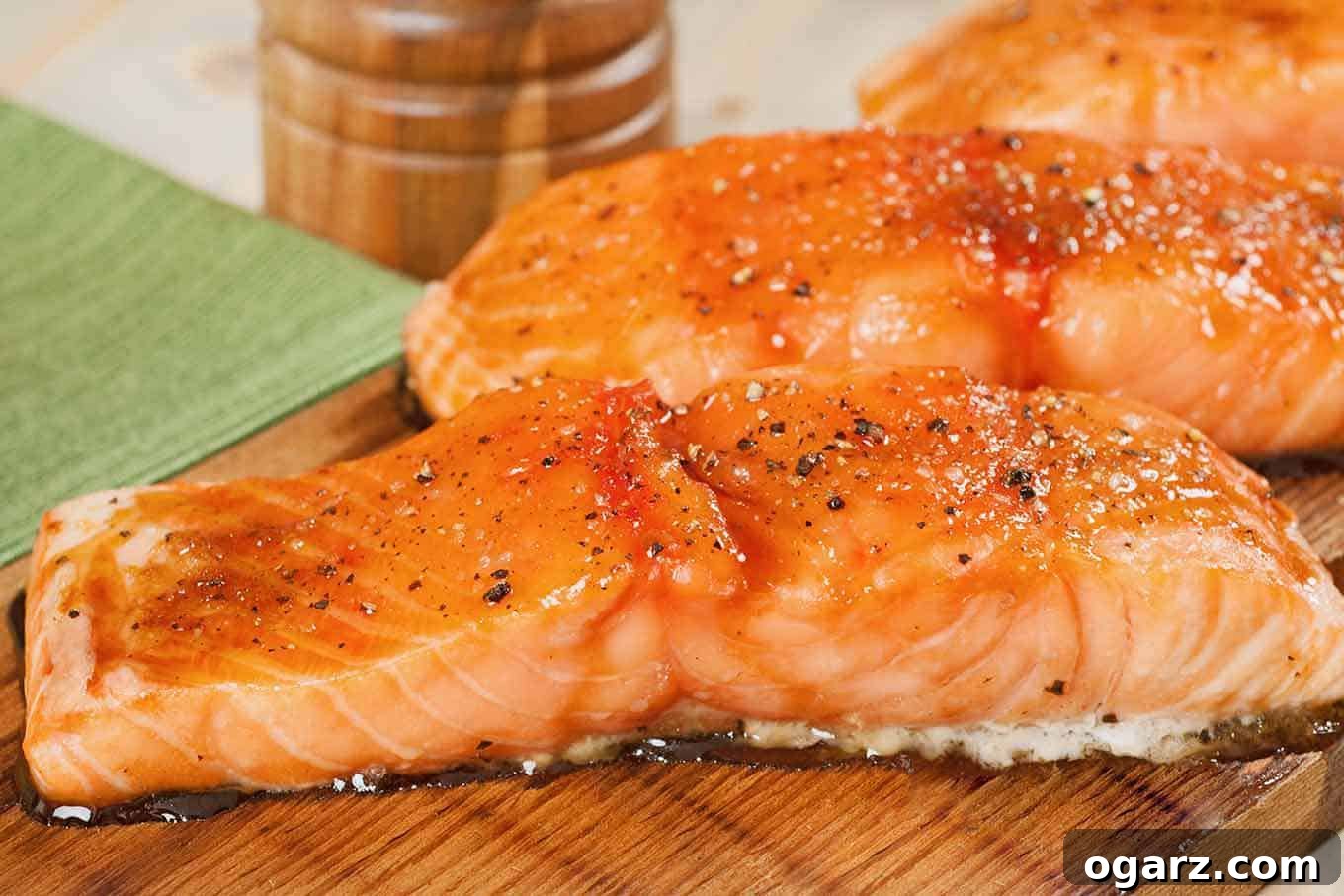 Smoky Cedar Salmon Perfection 3 A side view of two salmon fillets that have been seasoned and grilled on a cedar plank.