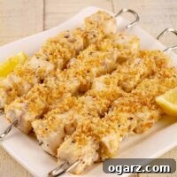 A serving platter filled with chunks of grilled swordfish on metal skewers, rolled in panko crumbs toasted in butter with garlic and lemon.