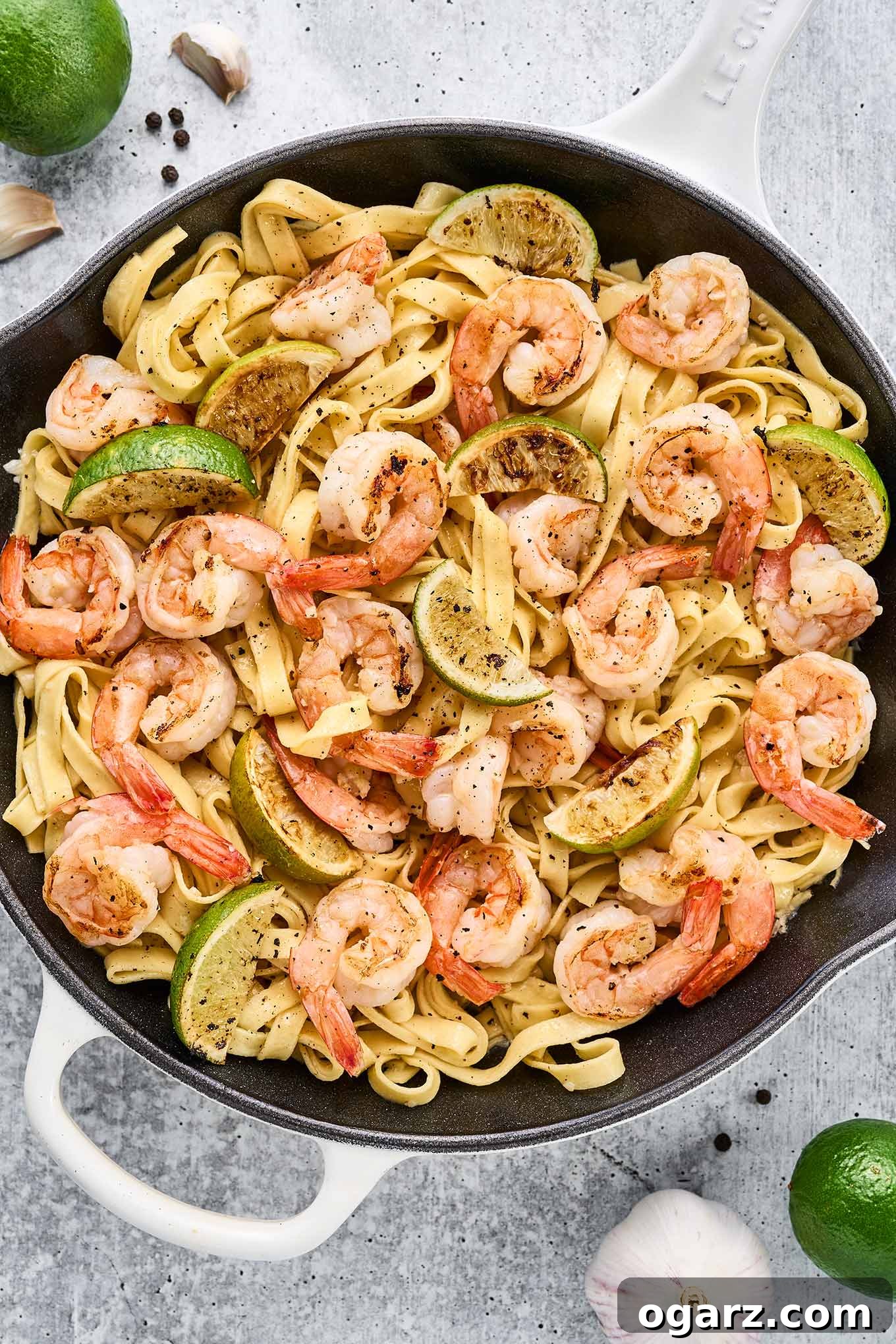 Zesty Garlic Lime Shrimp Pasta 2 A cast iron pan filled with fettuccine tossed with sautéed shrimp, pan-seared lime wedges, and a light and garlicky white wine sauce.