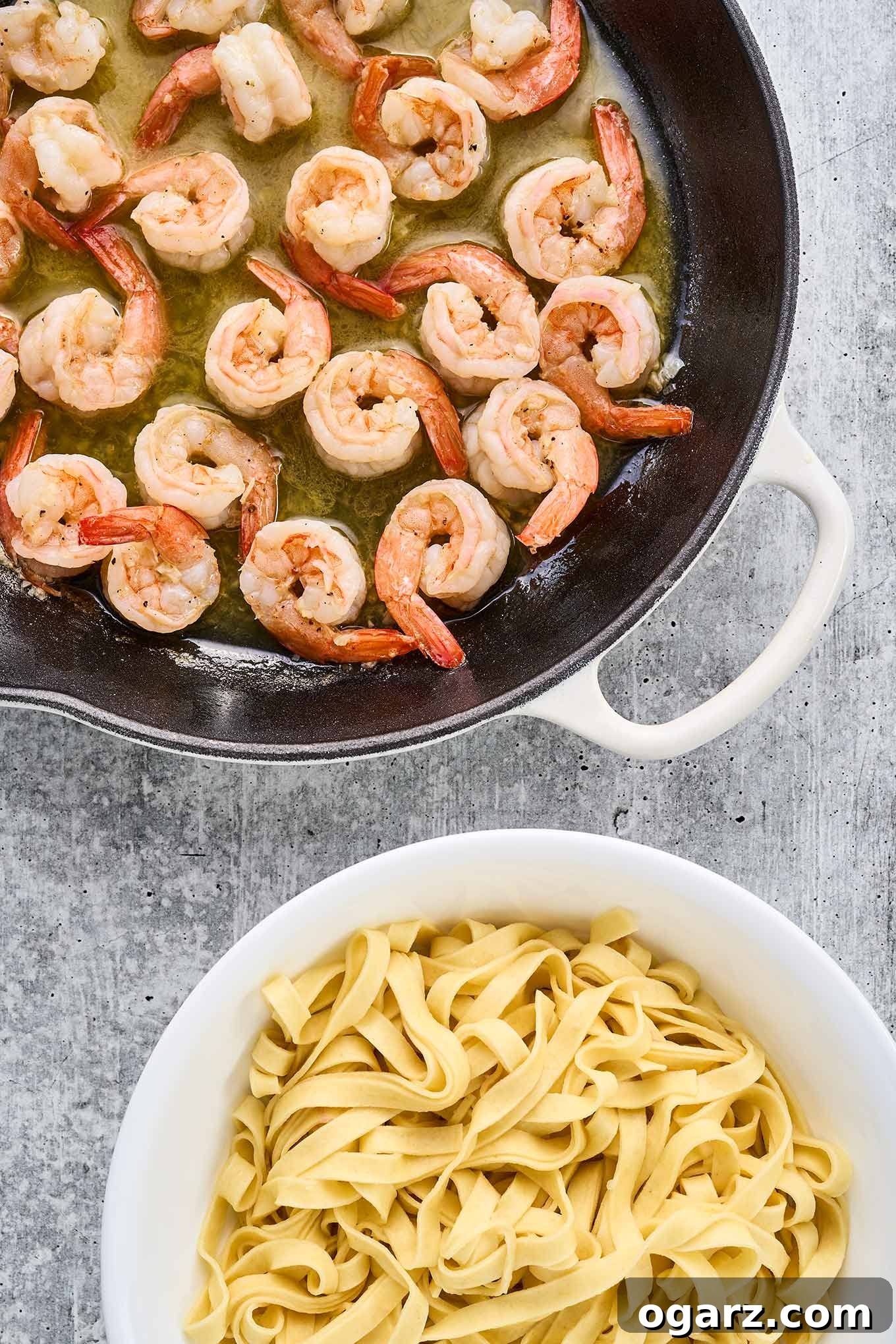 Zesty Garlic Lime Shrimp Pasta 4 A cast iron pan with sautéed shrimp in butter sauce next to a bowl of fresh fettuccine.