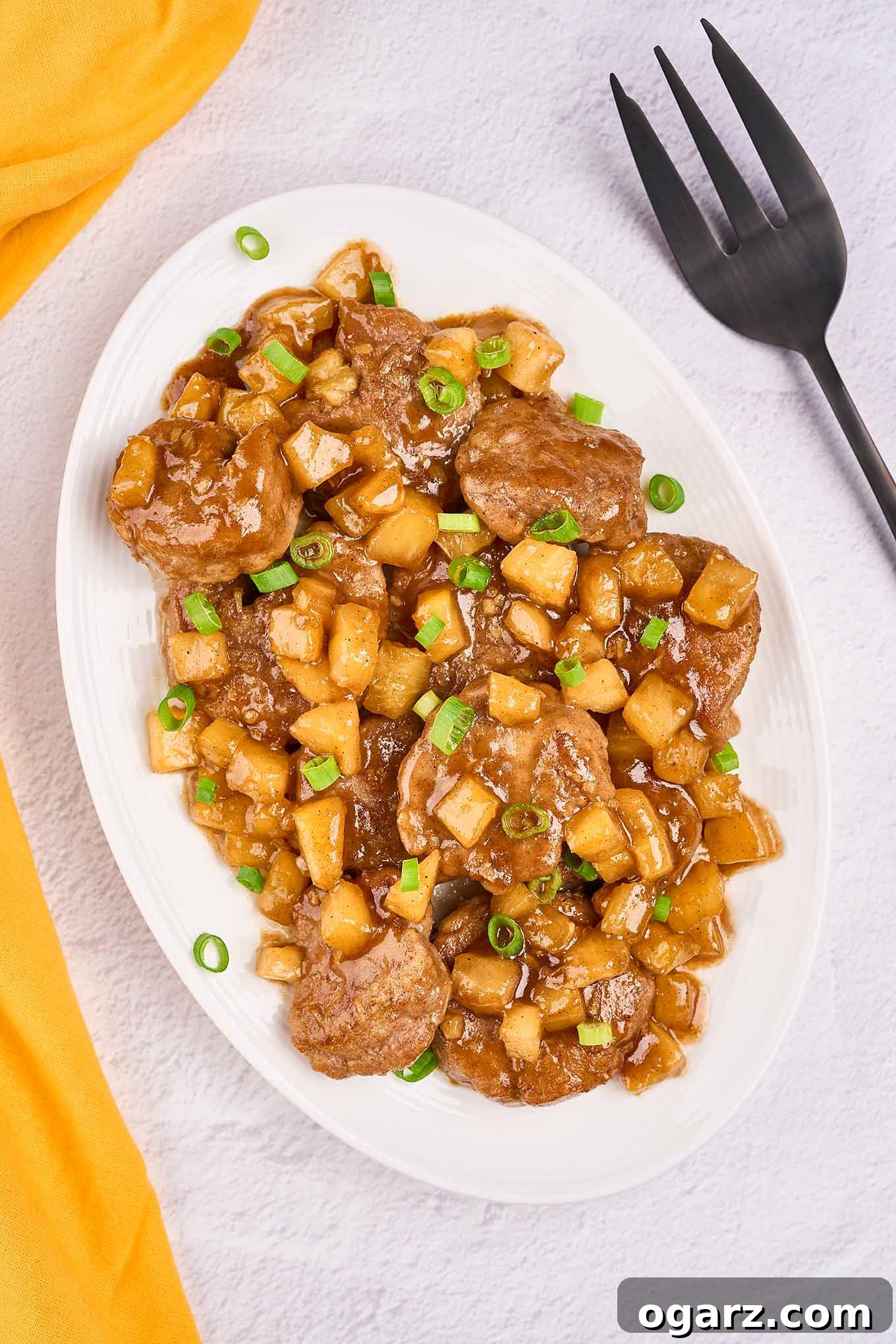 Tropical Pineapple Pork Skillet 2 An oval serving platter of Caribbean-style pineapple pork with tender pork medallions, pineapple chunks, and scallions in a sweet-savory rum sauce, ready to be enjoyed.