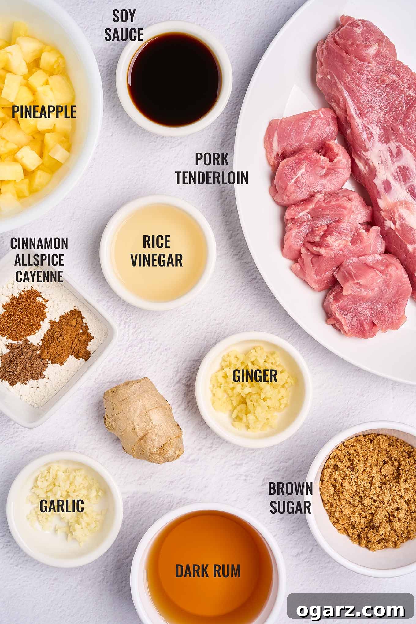Tropical Pineapple Pork Skillet 3 A labeled overhead view of the ingredients for Caribbean pineapple pork with rum sauce, including pork tenderloin, pineapple, rum, brown sugar, and a selection of aromatic spices.