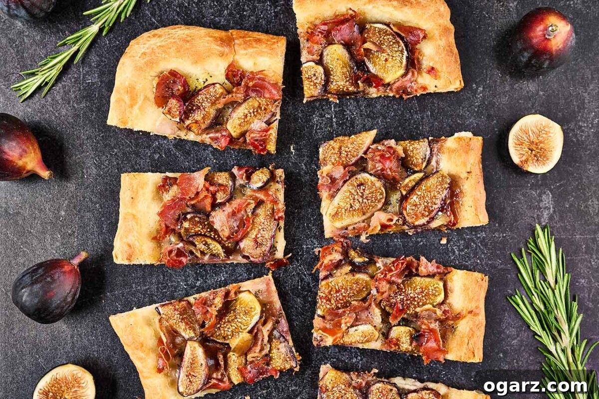 A rectangular fig and prosciutto pizza expertly cut into individual appetizer-sized squares, beautifully garnished with extra fresh figs and sprigs of fragrant rosemary, ready to be served and enjoyed.