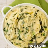 A smaller view of creamy Colcannon with kale, onions, and scallions, in a white bowl.