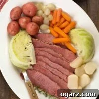 A serving platter with New England boiled dinner; sliced corned beef brisket, cabbage wedges, baby red potatoes, baby carrots, pearl onions, and turnips.