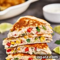 Golden chicken and cheese quesadillas, expertly cut into wedges and neatly stacked on a cookie sheet, ready to serve alongside vibrant lime slices and a small bowl of creamy sour cream for dipping.