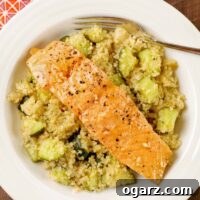 An overhead view of a bowl of quinoa combined with roasted zucchini and topped with a roasted, honey-glazed salmon fillet.