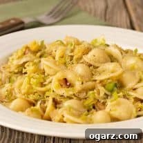 A plate orecchiette pasta tossed with sautéed shredded Brussels sprouts and bacon, a fork and napkin in the background.
