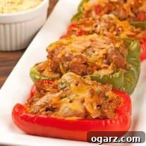 Turkey sausage and orzo stuffed bell peppers baked with melted cheese, served on a rectangular white platter.