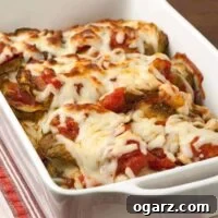 Baked Italian-style eggplant casserole in a white dish, layered with tomato sauce and melted mozzarella cheese.