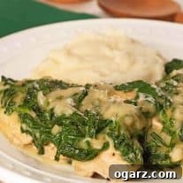 Easy chicken Florentine topped with creamy spinach sauce, served with a side of mashed potatoes on a white plate.