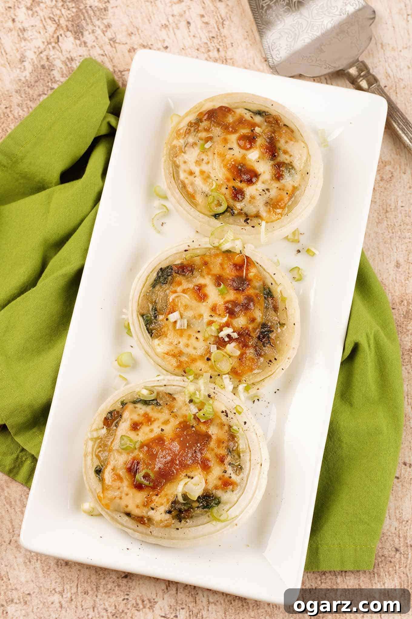 An overhead view of vibrant baked sweet onion halves, brimming with a creamy, rich sauté of fresh spinach and earthy mushrooms, all crowned with golden, melted cheese.