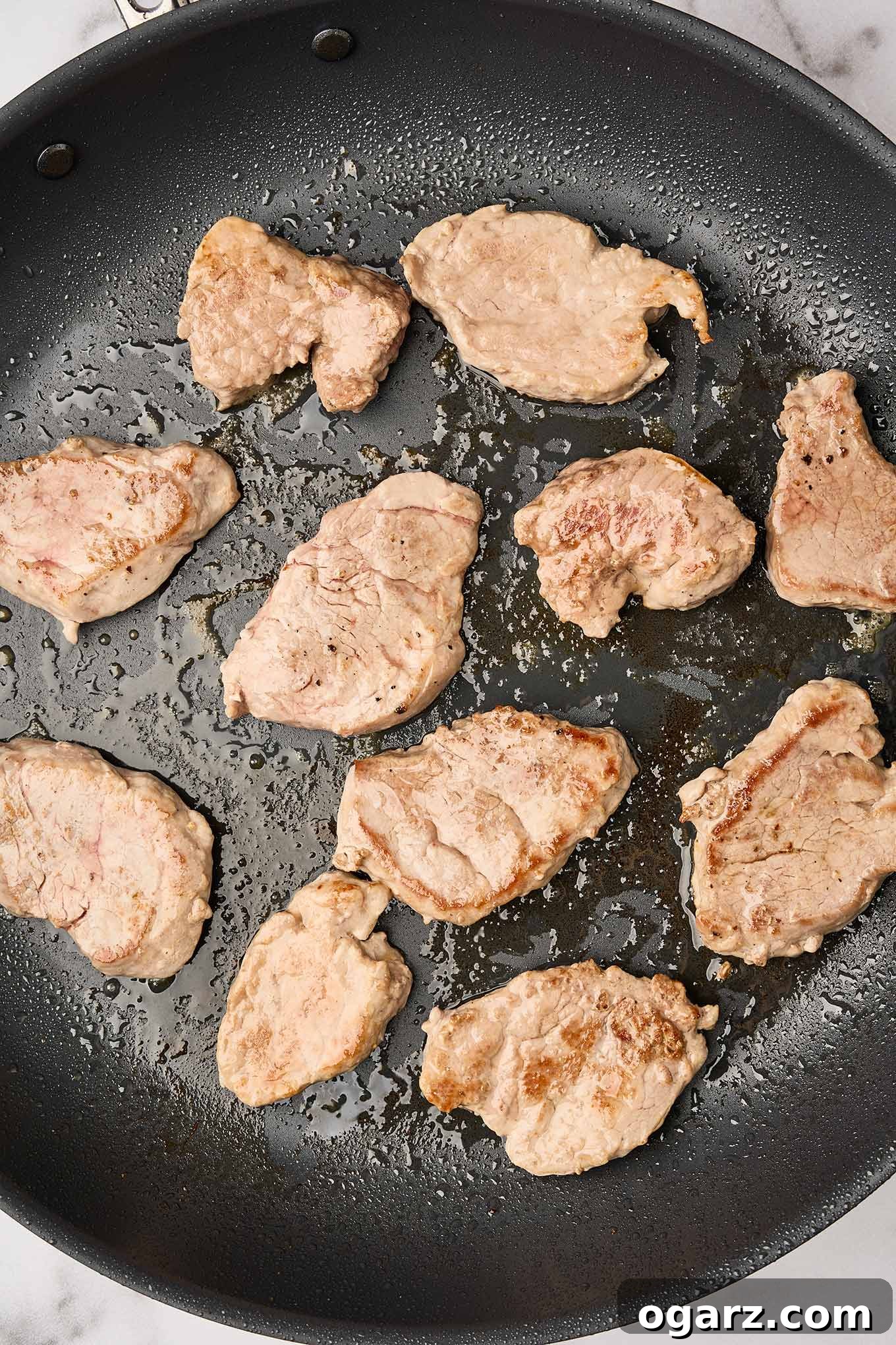 Pork medallions in a skillet, searing on a second side, ready to be transferred to a plate while the curry sauce is being made.