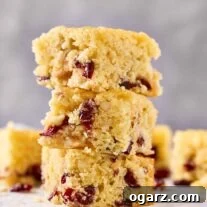 Zesty Cranberry Orange Squares 8 Three cranberry bars stacked on a cooling rack, showing their dried cranberries, almonds, and orange zest.