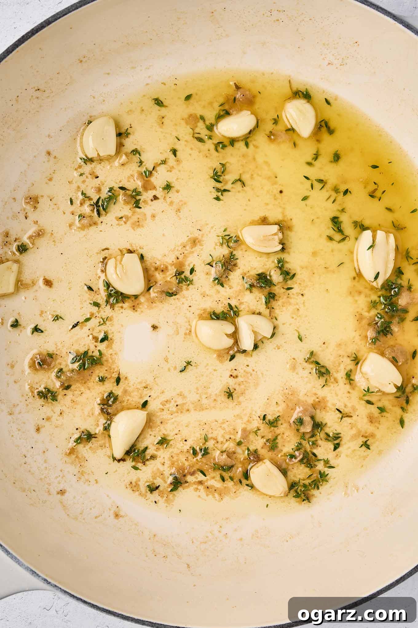 Rustic Slow-Braised Chicken and Potatoes 5 Lightly crushed garlic cloves and fresh thyme sprigs gently sautéing in dry white wine within the pan, after the chicken has been browned and removed.