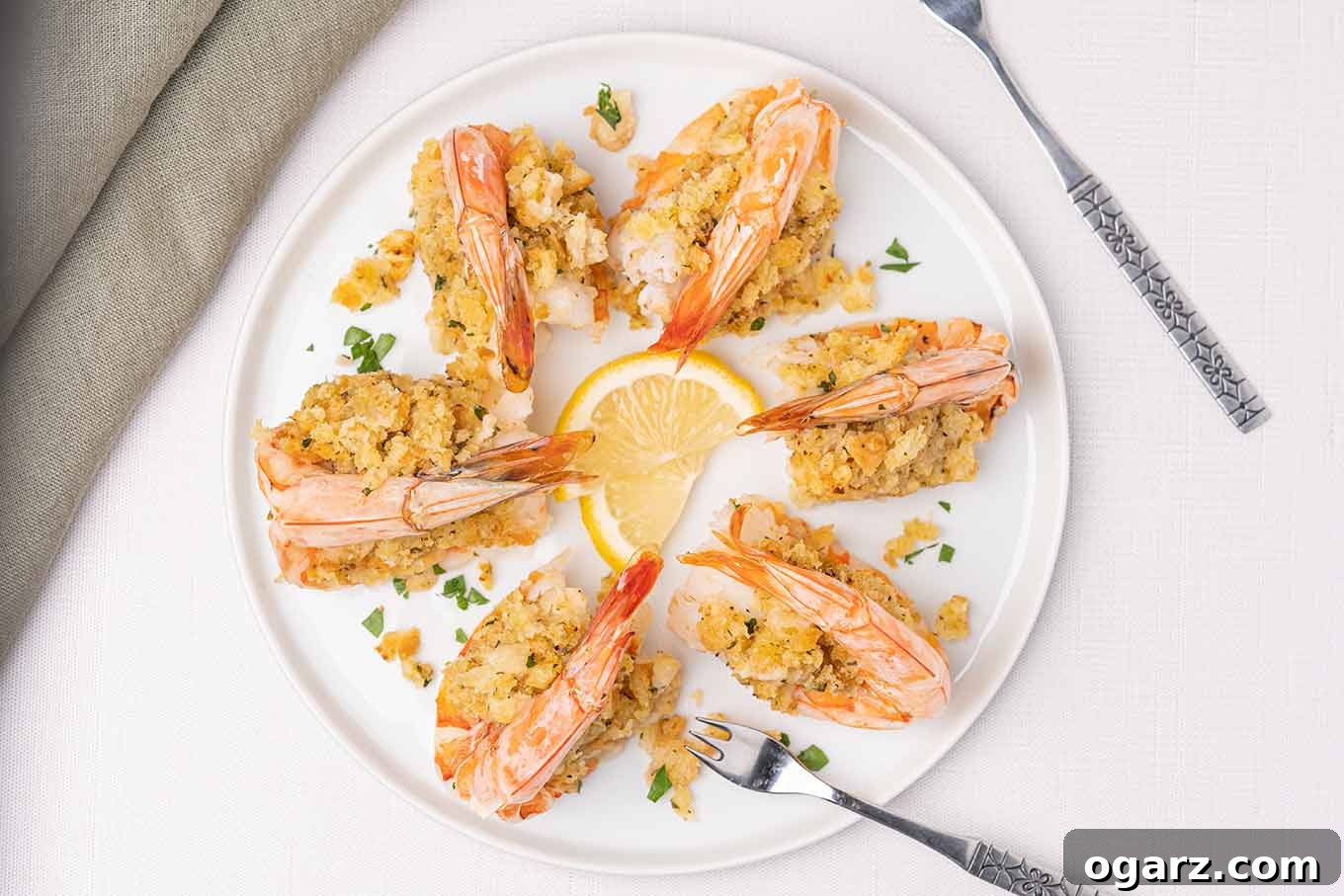Six perfectly baked stuffed shrimp, garnished with fresh lemon wedges and parsley, ready to be served alongside elegant seafood forks and linen napkins.