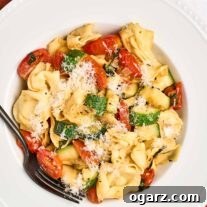 Speedy Cheese Tortellini with Garden Vegetables 8 An overhead view of a bowl of cheese tortellini combined with sautéed zucchini, grape tomatoes, and fresh basil, topped with grated Parmesan.